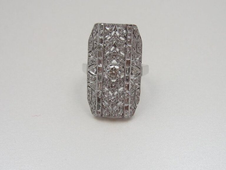Importante BAGUE «plaque» «dentelle» en or gris (750 millièmes) ajouré, serti de diamants taille brillant dont un, au centre, plus important et deux lignes de diamants baguette