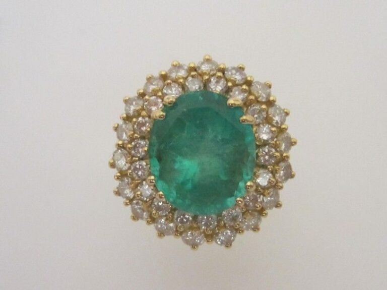 Importante BAGUE «Pompadour» en or jaune (750 millièmes) serti d'une émeraude de forme ronde entouré de deux lignes de diamants taille brillan