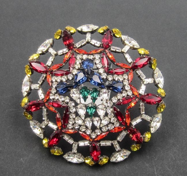 Importante broche en médaillon ajourée ornée de pierres blanche, rouge, jeune, bleu et vert