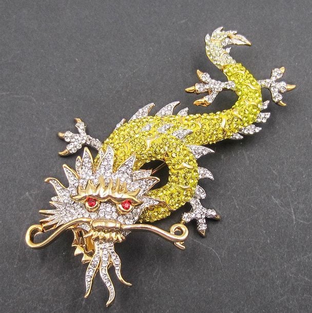 Importante broche en métal agrémentée de pierres jaune, blanche et rouge représentant un drago
