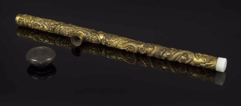 IMPORTANTE PIPE À OPIUM EN BRONZE DORÉ DOTÉE D'UN FOYER SIGNÉ WAN CHENG Chine, Dynastie Qing, Époque XIXe siècle La pipe en bronze moulé et doré est adjointe d'embouts de jade jadéite (l'un deux lacunaire), présente une plaquette intégrée (non rapportée, comme d'accoutumée, mais comprise dans la fonte) et un foyer en grès (vraisemblablement de Yixing