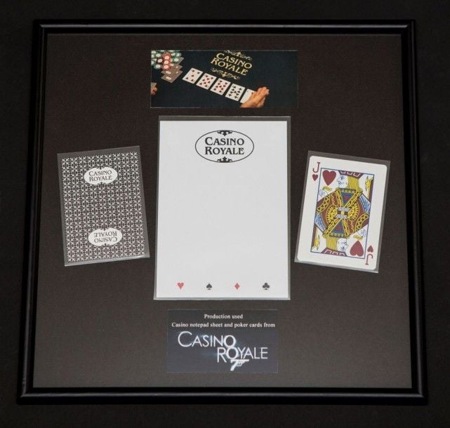 James Bond Props - Cartes à jouer et feuille de note, Casino Royale 2006 Grande-Bretagne Dimensions des cartes: 8,8 x 6,3 cm Dimensions de la feuille de note: 14,7 x 10,5 cmDimensions du cadre: 30 x 30 cm Lorsque le terroriste le Chiffre (Mads Mikkelsen) organise une partie de poker avec un enjeu de plusieurs millions de dollars, James Bond (Daniel Craig) voit une excellente occasion de faire tomber son ennem