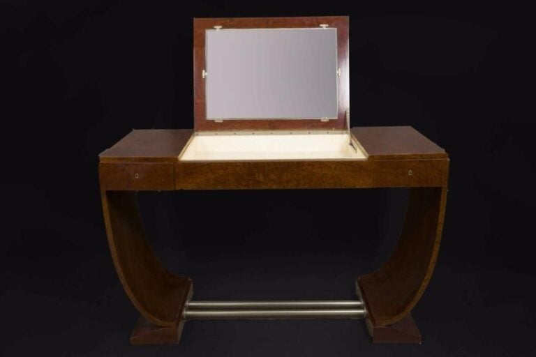 Jules LELEU (1883-1961) Coiffeuse en placage de loupe d'amboine à plateau rectangulaire ouvrant en partie centrale par un abattant dévoilant un miroir et un casier double, entre deux tiroirs latéraux en ceinture sur un piétement lyre à double traverses tubulaires en métal chrom