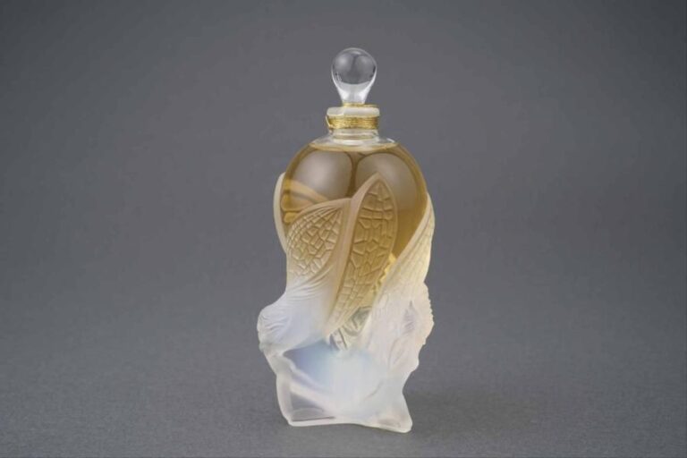 LALIQUE FRANCE  Modèle "Les Elfes" Flacon de parfum en cristal en partie opalescent à décor de trois elfes ailées soutenant une amphore de forme ovoïde avec son bouchon goutt
