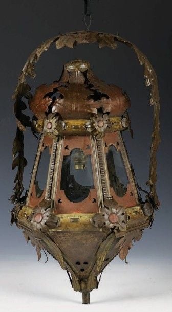 Lanterne en tôle découpée, repoussée et polychrome; de forme octogonale, elle est à décor de feuillages et fleurs stylisés et est suspendue par une anse articulée à feuillage