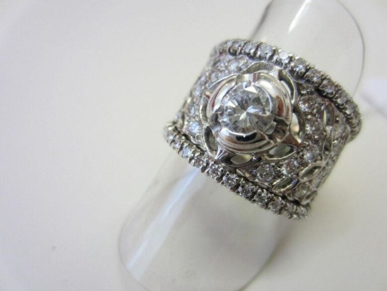 Large BAGUE en or gris (750 millièmes) ajouré serti de diamants taille brillant dont un au centre plus importan
