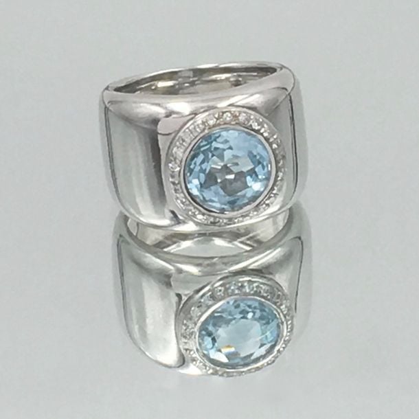 Large BAGUE en or gris (750 millièmes) serti d'une topaze bleue ronde entourée de diamants taille brillan