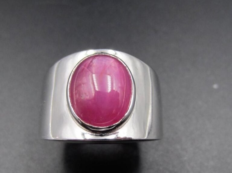 Large BAGUE en or gris (750 millièmes) serti d’un rubis cabochon étoilé (choc sur la base du rubis