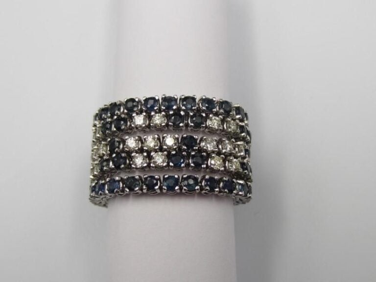 Large BAGUE souple en or gris (585 millièmes) 14 carats, composée de cinq lignes serties de saphirs ronds alternés de diamants taille brillan