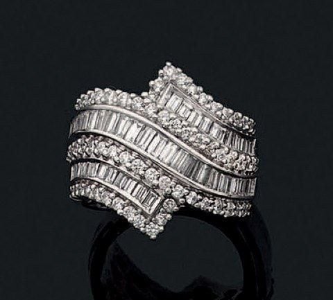 Large BAGUE «volute» en or gris (750 millièmes) serti de diamants taille brillant, taepers et baguette