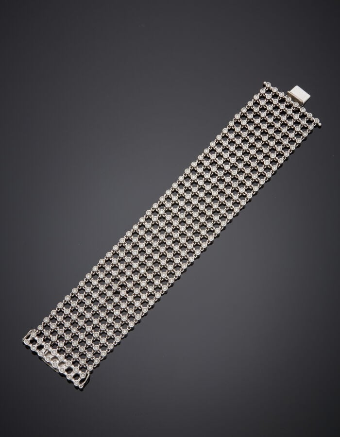 Large BRACELET manchette "résille" or gris (750‰) articulé et ajouré, serti de…