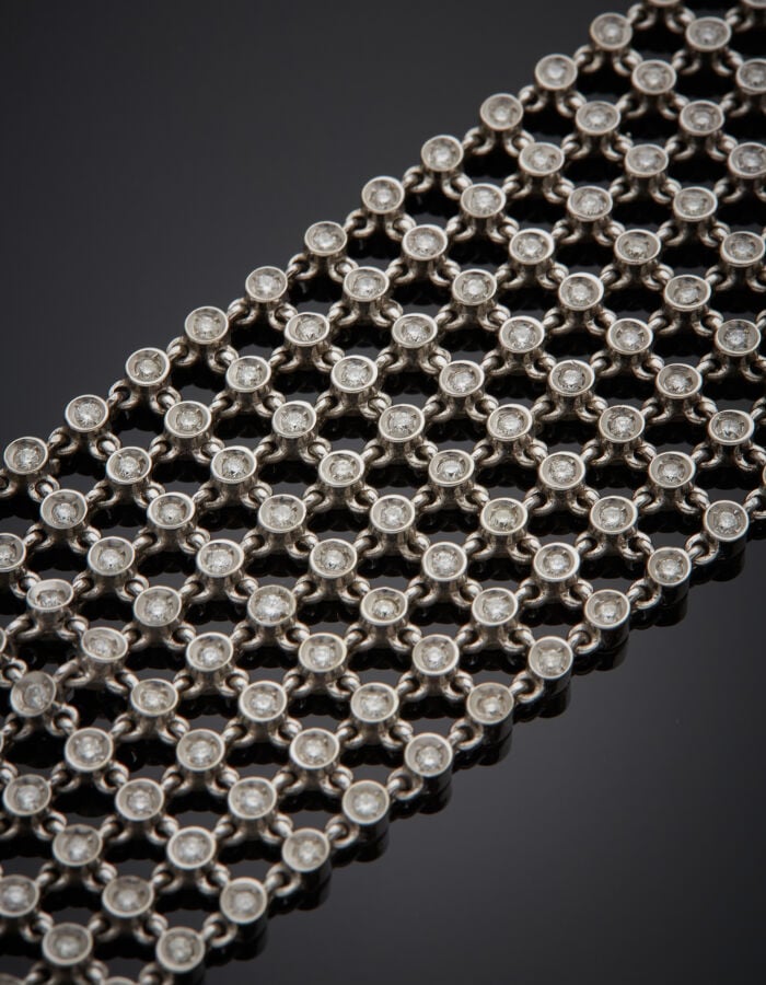 Large BRACELET manchette "résille" or gris (750‰) articulé et ajouré, serti de…