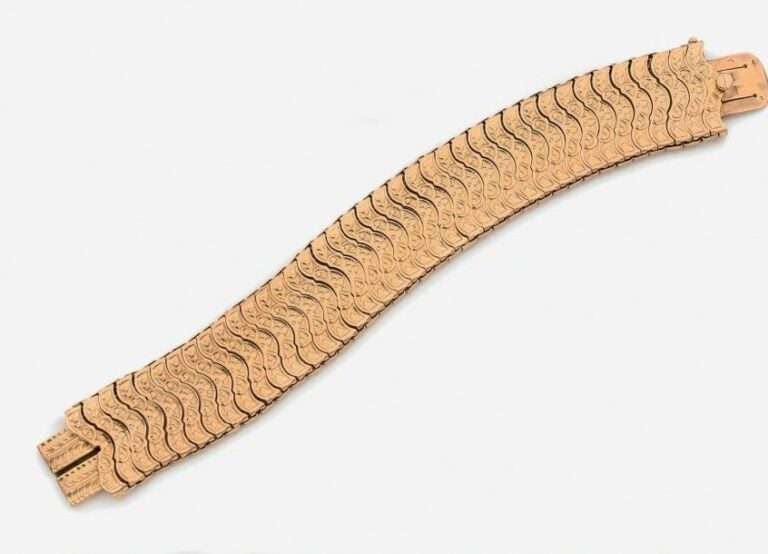 Large BRACELET manchette souple en or jaune (750 millièmes) ciselé de volutes, à maillons légèrement coulissant