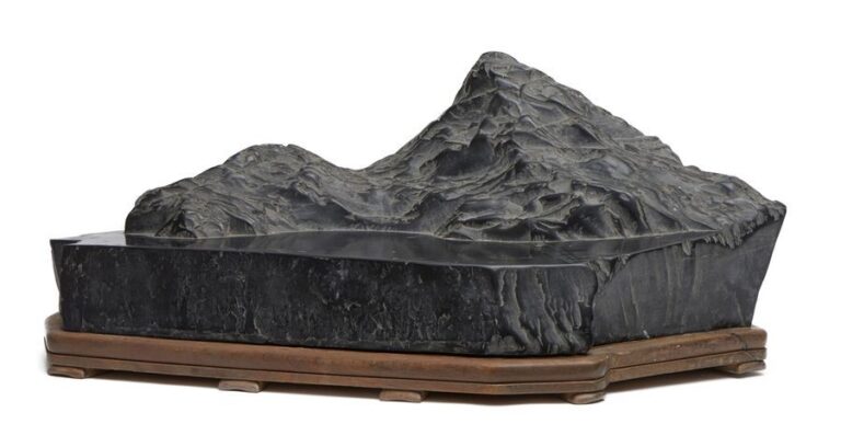 Large et exceptionnelle pierre suiseki noire sur un socle en bois représentant des montagnes près d'un la