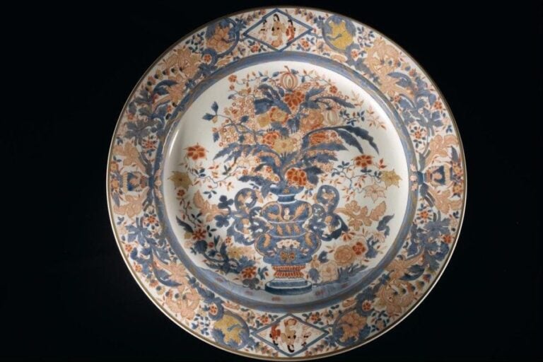 Large plat circulaire Imari à décor émaillé rouge et bleu cobalt sous couverte, le cavetto centré d'un vase fleuri, l'aile ornée de bouquets fleuris et de personnage