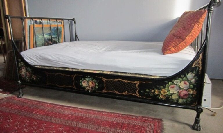 Lit à barreaux en fer forgé laqué noir et polychrome à décor de fleurs; pieds griffe