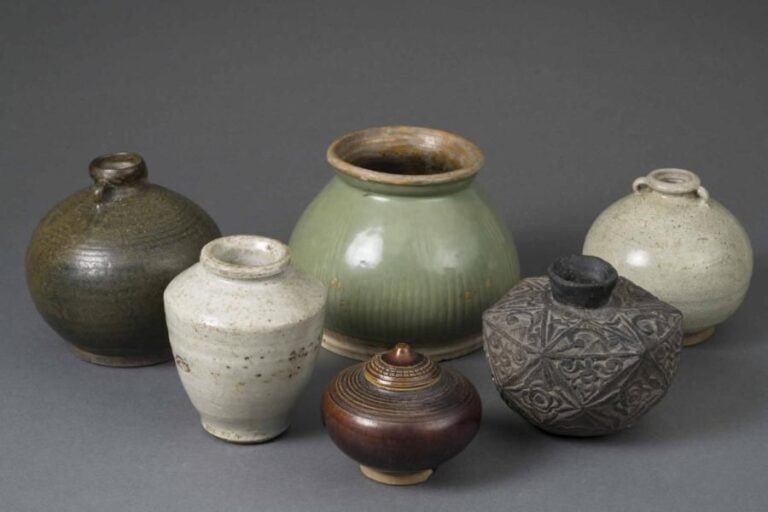 LOT DE CERAMIQUES THAILANDAISES ET INDONESIENNES Thaïlande et Indonée, XVe à XIXe siècle Il comprend: > 1 jarre ovoïde à oreilles en grès porcelaineux à couverte céladon / bleu de type Sawankalok, Thaïlande; > 1 jarre à panse fuselée, épaule carénée, lèvre ourlée de type Sawankalok, Thaïlande; > 1 autre jarre ovoïde à oreilles en grès porcelaineux à couverte brune de type Sawankalok, Thaïlande; > 1 jarre à panse conique godronnée, lèvre renversée, couverte en partie en céladon; > 1 pot à eau ovoïde et facetté en céramique noire, décor géométrisé de fleurs et d'étoiles, vraisemblablement Indonésie; > 1 pot couvert ovoïde et conique à cercles concentriques en grès à couverte beige / jaune de type Sukhotaï, Thaïland