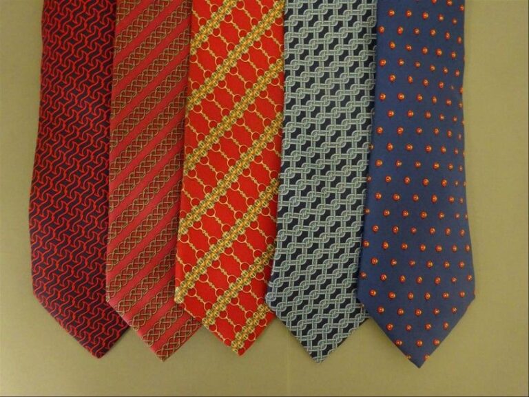 Lot de cinq cravates en soie, trois dans les tons rouge, deux dans les tons bleu, à décor de motifs géométriques variés, dont chevrons, chaînes et pois