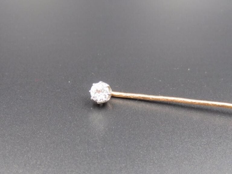Lot de deux EPINGLES A CRAVATE en or jaune (750 millièmes) :      - une serti d’un diamant taille ancienne        Travail français, vers 1900        Poids brut : 2,2 g             - l’autre d’un cabochon de corail        Poids brut : 1,8 g
