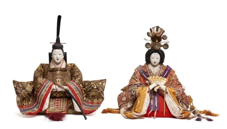 Lot de deux grandes poupées ningyo traditionnellement utilisées lors du festival des poupées (hinamatsuri): Un empereur et son impératrice assis sur le sol et habillés de kimonos composés de plusieurs couches de vêtements de couleur viv