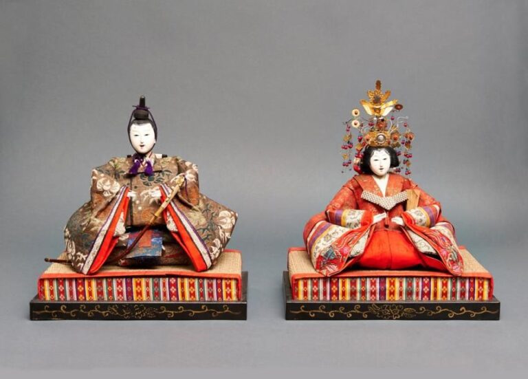 Lot de deux poupées japonaises (ningyo) traditionnellement utilisées lors de la fête des poupées (hinamatsuri): un empereur et une impératrice assis sur un tatami et vêtus de brocar