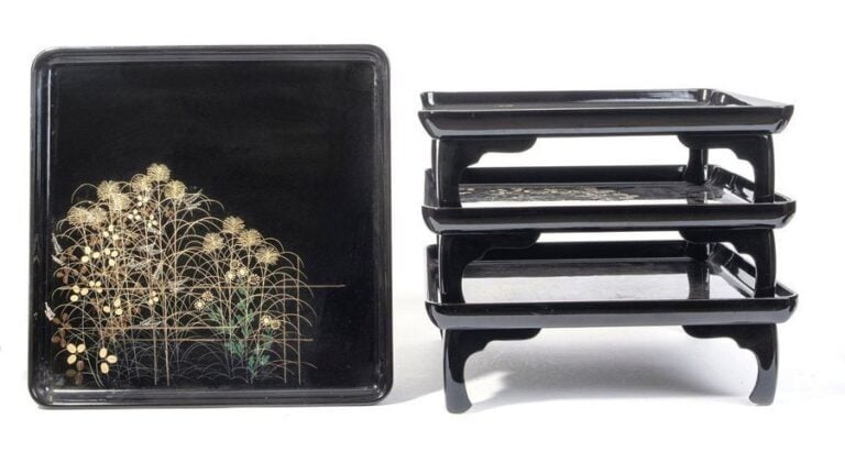 Lot de quatre tables basses zen laquées noir, à décor de feuilles d'automne et fleurs, derrière une barrière en bambo