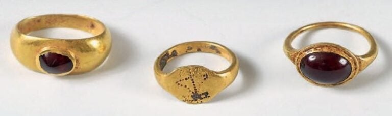 Lot de trois bagues d'enfants, dont deux ornées d'un cabochon en grenat et une au chaton gravé d'un monogramme piquet