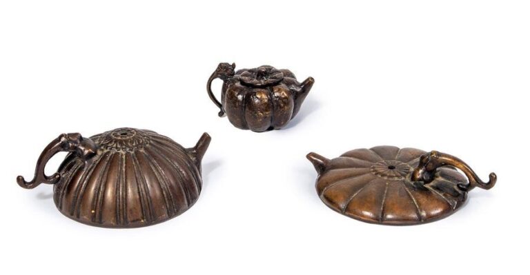Lot de trois compte-gouttes en bronze : une théière en forme de melon avec une marque inférieure : So'un ; une «théière» plate en forme de fleur stylisée, et une «théière» en forme de dôm