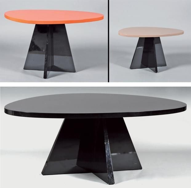 Lot de trois tables modèle « Mercedes », l'une de grande taille pour salle à manger à plateau noir sur piétement cruciforme en bois laqué noir et plateau à découpe ovalisé, deux plus petites, l'une à plateau ovalisé orange sur piétement cruciforme et l'autre à piétement ovalisé crème sur piétement cruciform