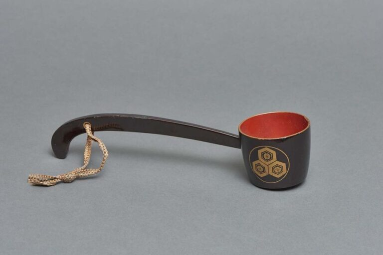 Louche garnie de laque noire utilisée à l’origine pour donner à boire aux chevaux (mabishaku) décorée de laque dorée maki-e et d’un emblème figurant un motif « carapace de tortue » (mitsu morikikk? ni hanakaku mon