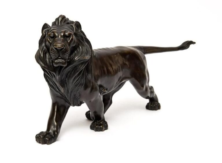 Lourde figurine en bronze foncé figurant un lion marchant à grand pa