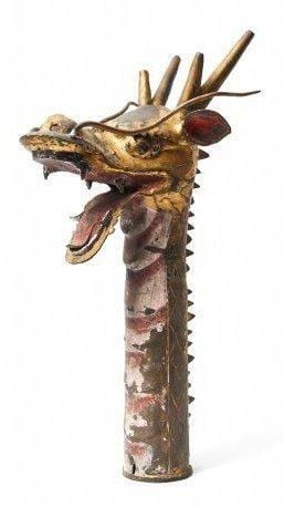 Lourde sculpture de métal doré clairsemée de pigments rouges représentant une tête de dragon à corne, avec un long cou et la gueule grande ouvert