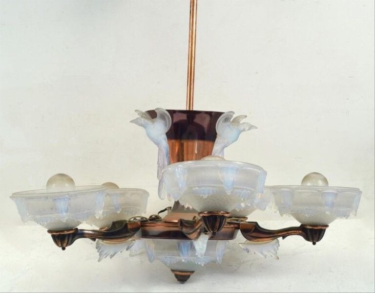 Lustre Art Déco à cinq bras à armature en cuivre et bobèches et coupelle supérieure en verre moulé pressé opalescent ; les bobèches à décor de stalagtites et de résilles type "nid-d'abeille" ; la coupelle supérieure est appliquée de martin-pêcheurs traités en ronde-bosse