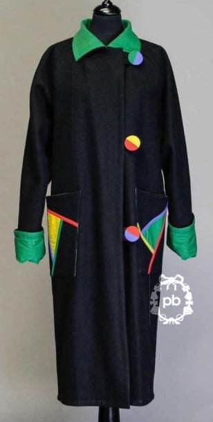 MANTEAU mi-mollets en lainage noir rehaussé de sergé de coton multicolore, col rabattu sur boutonnage à brides asymétrique recouvert, deux poches plaquées, revers au bas des manches longues raglan (env TM)
