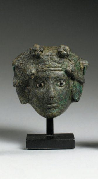 MASCARON Petit masque représentant une ménade, au visage triangulaire, coiffée de pampres, les yeux incrusté