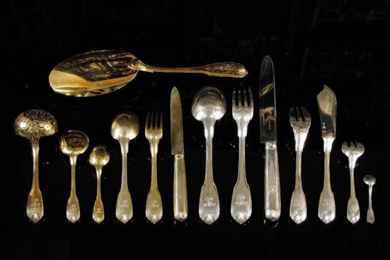 Ménagère en argent et vermeil de 221 pièces composée de 26 fourchettes, 26 couteaux et 13 cuillers de table ; 16 couverts à poisson ; 12 fourchettes à huîtres, 12 cuillers et 12 fourchettes à entremets, 12 couteaux à fromage, 12 couteaux à fruits, 12 pelles à glace, 12 cuillers à café, 13 cuillers à moka et 27 pièces de service ; modèle à filets et coquilles, les spatules chiffrées BEM Par Puiforcat, poinçon Minerve Poids hors couteaux : 10 909 g