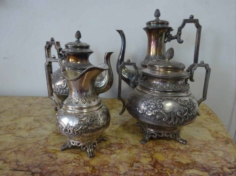 METAL ARGENTE - Service à thé et à café en métal argenté à décor floral exécuté au repoussé et frétels formant pommes de pi