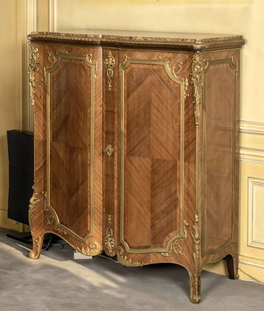 Meuble à hauteur d'appui en placage de bois de rose; la façade galbée ouvrant par deux portes; garniture de bronze ciselé doré; chutes aux satyre