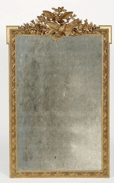 Miroir dans un cadre en bois sculpté et doré; à l'amortissement les attributs de l'Amour; montants à frises rubanée