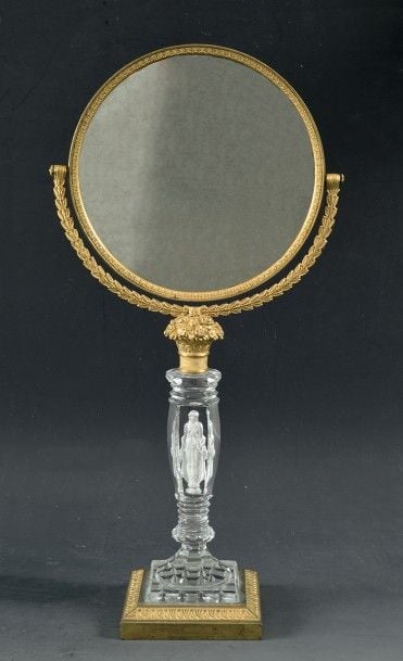 Miroir de table pivotant cerclé de bronze ciselé et doré, articulé sur une monture semi-circulaire en bronze ciselé et doré en forme de guirlandes de feuilles de laurier issue d'une corbeille de fleurs en bronze ciselé et dor