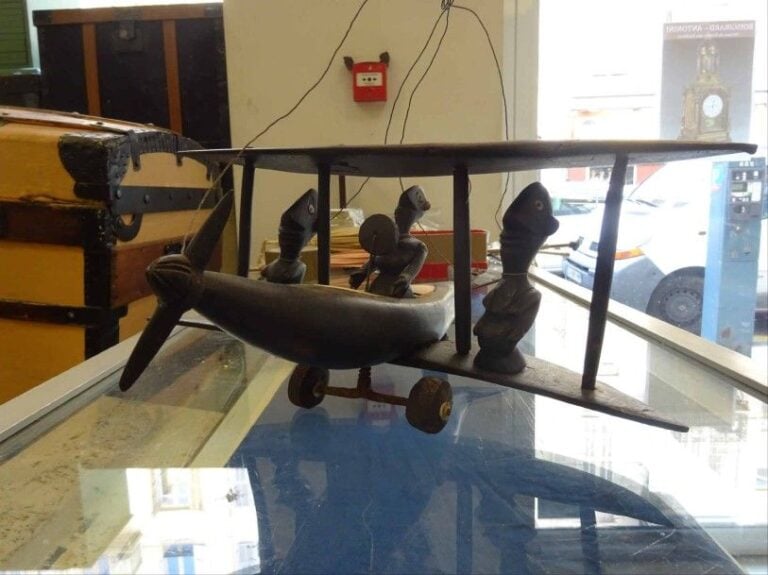 MOBILE / JOUET AFRICAIN FORMANT AVION AUX PERSONNAGES Travail d'Afrique noire Golfe de Guinée vraisemblablement des années 1950 Bois sculpté avec incrustations de plaques d'os introduisant un jeu sur les contrastes de couleurs figurant un avion aux trois passagers les roues et l'hélice articulées