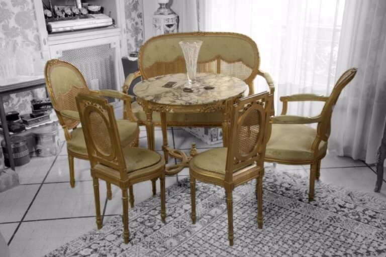 Mobilier de salon en bois doré de style Louis XVI à beau décor de motifs feuillagés et rubans noués comprenant :  - un canapé à dossier canné 98x125x53 cm - une table circulaire reposant sur 4 pieds fuselés à entretois