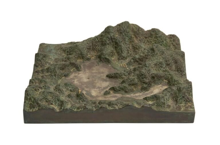 Modèle en bronze coulé de forme rectangulaire figurant un paysage avec une montagne, un lac et un petit villag