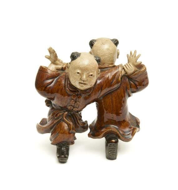 Objet décoratif okimono en céramique figurant deux jeunes garçons chinois (karako) portant un habit garni de glaçure brune et jouant ensembl