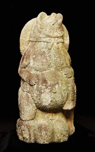 Ornement de jardin cocasse, en granit, représentant un tanuki (chien viverrin) avec un gros ventre, un chapeau de pèlerin pendant autour du cou, une flasque d'alcool et un sac à provisions à la mai