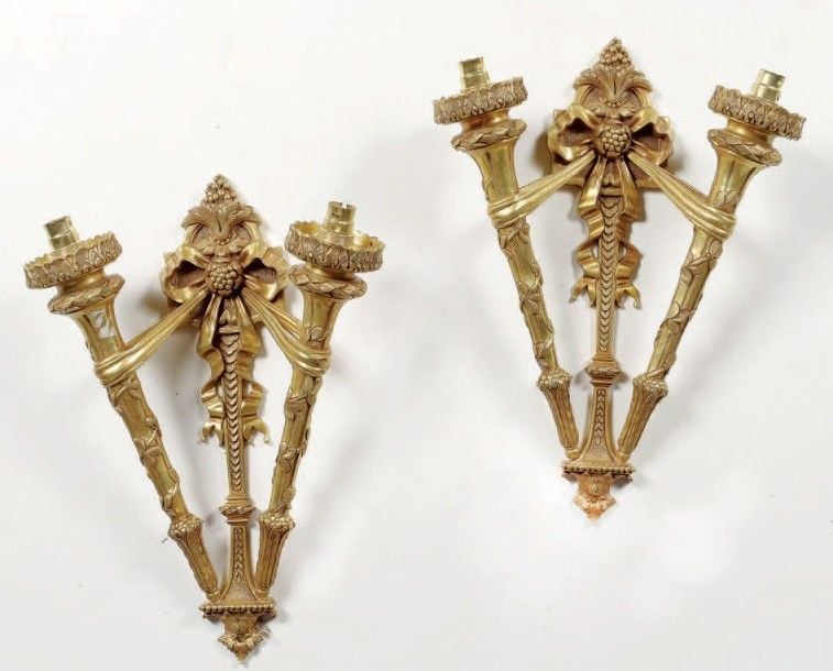 Paire d'appliques à deux lumières en bronze ciselé et doré; les fûts supportant les bras de lumières en forme de torches par des ruban