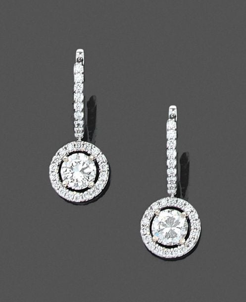 •Paire de BOUCLES d'OREILLES «dormeuses» circulaires en or gris (750‰) serti de diamants taille brillant, dont deux pesant 0,6 carat chacu