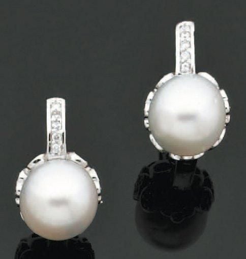 Paire de BOUCLES D'OREILLES en or gris serti d'une perle de culture blanche surmontée d'un alignement de diamants, à motifs latéraux de fleurette