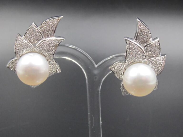 PAIRE de BOUCLES D'OREILLES «fleur stylisée» en or gris (750 millièmes) orné d'une importante perle de culture blanche de forme ronde entourée de pavages de diamant