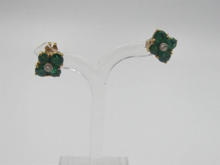 •PAIRE de BOUCLES D'OREILLES «fleurettes» en or jaune (750‰) serti d'un diamant entouré de quatre émeraude
